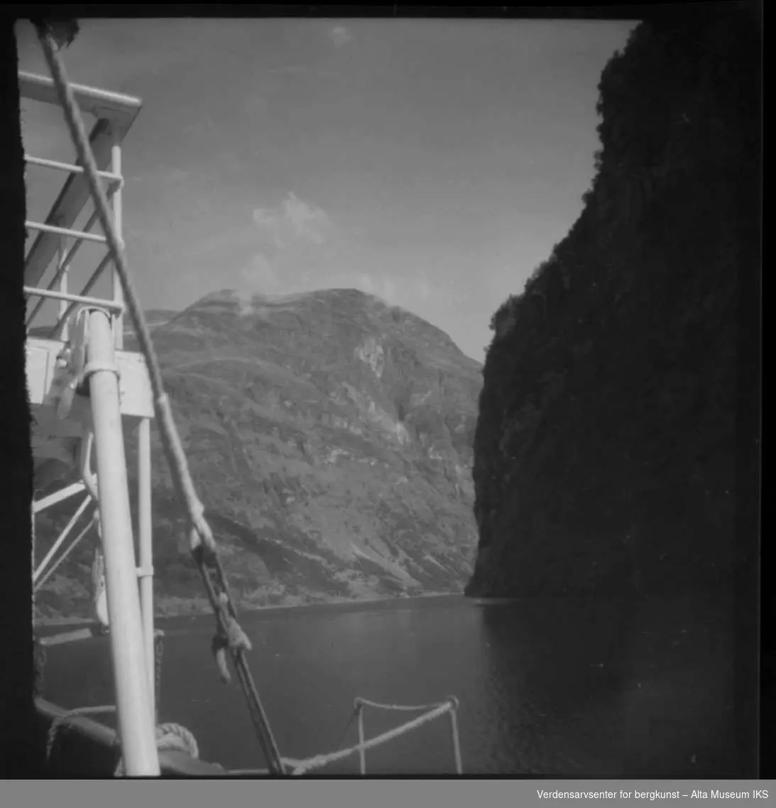 Bilde av bratte fjell og hav i Geirangerfjorden fra båt.