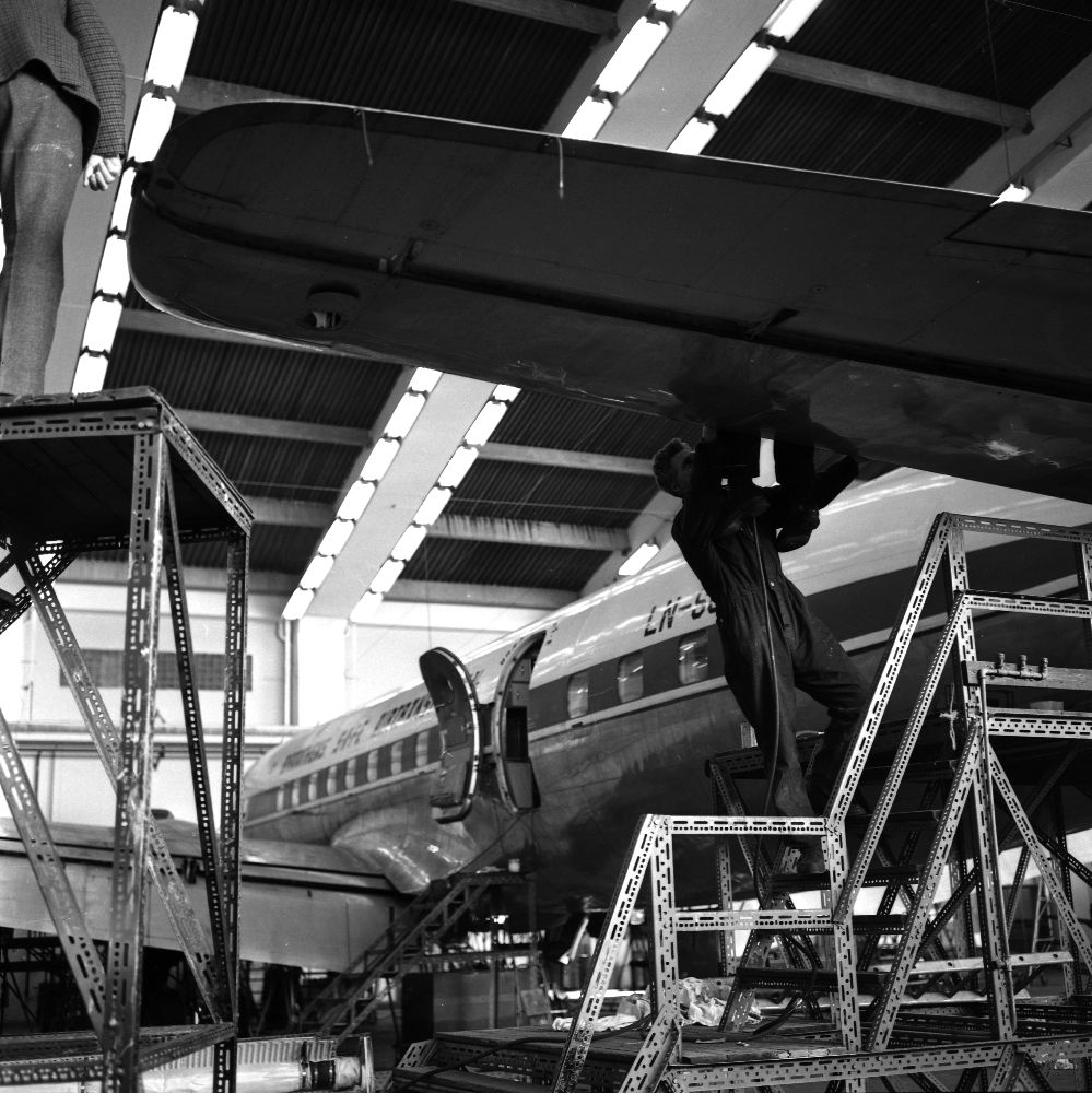 Landskap. I Braathens SAFE's tekniske avdeling står et fly i hangar for vedlikehold. En person sjekker halepartiet.