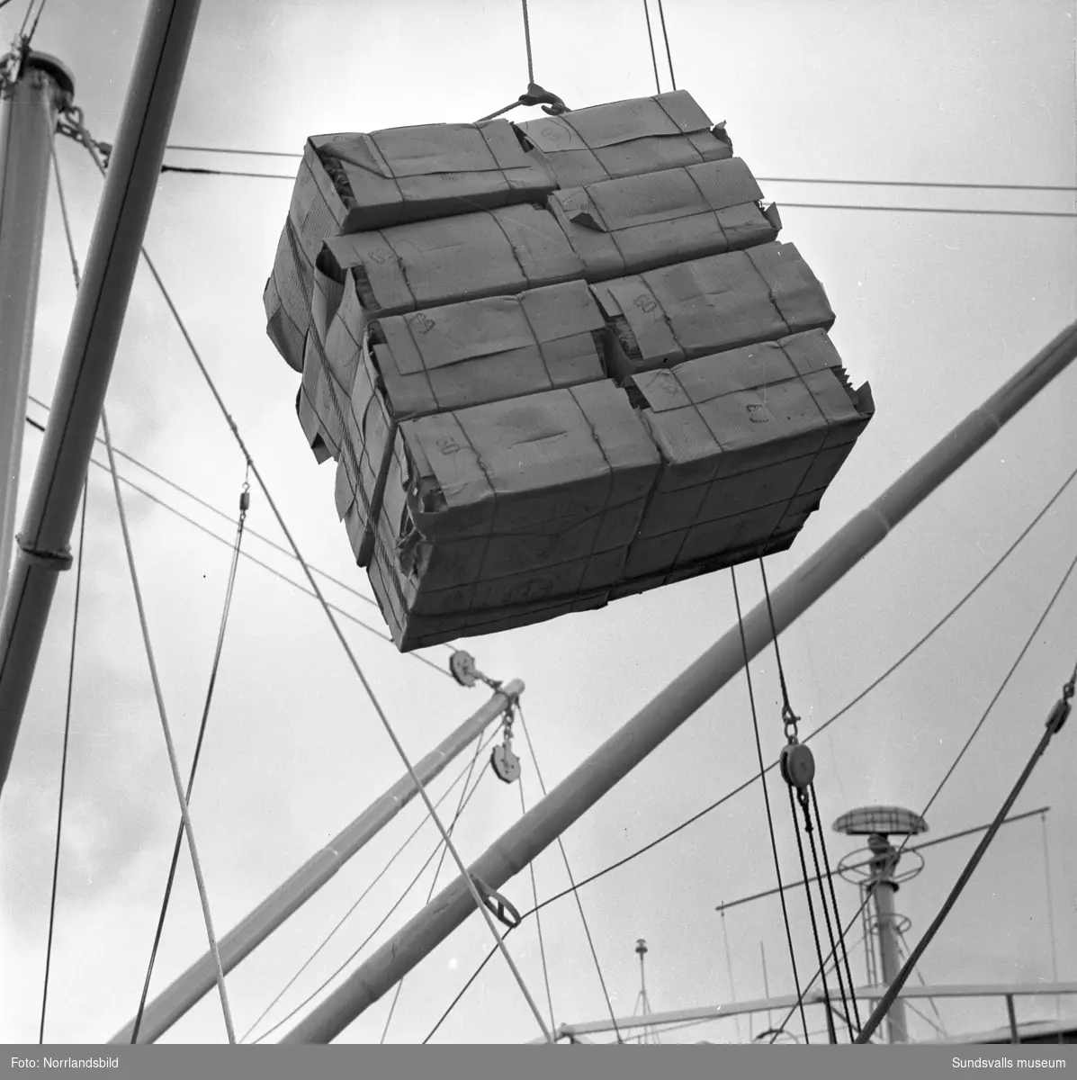 Bilder till ett reportage om exporten vid Östrands pappersfabrik. En båt lastas med massabalar, stuveriarbetare har matrast.