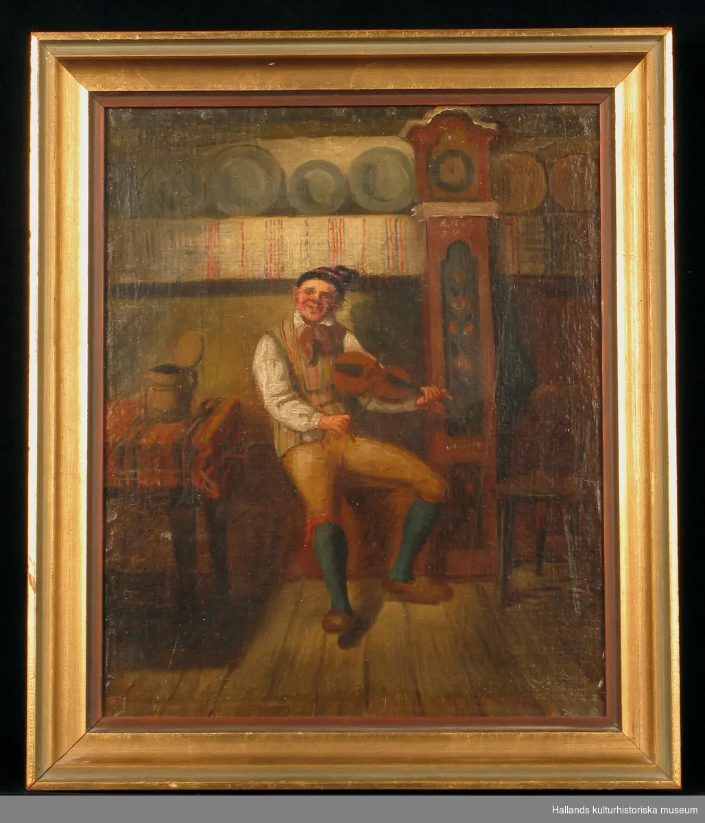 Oljemålning föreställande August Bondesson spelande fiol i en ryggåsstuga. Guldfärgad träram. Av ritmästare Carl Gustaf  Holmgren.