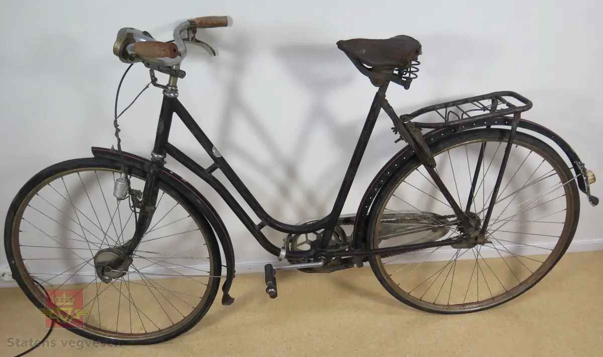 Tråsykkel, damemodell. Har to hjul, styre, sete, pedaler, frontlykt, ringeklokke, bagasjebrett, dynamo og refleks bak. Svart med rød staffering. Brunt sete og røde holker på styret. Sykkelen er i hovedsak lagd av metall, gummi og skinn.
Emblem med teksten: REIDAR KVAM Ø. GAUSDAL MIL.