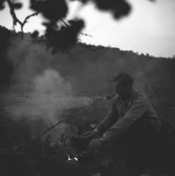 Eino Drannem sitter ved et leirbål og koker kaffe mens han r