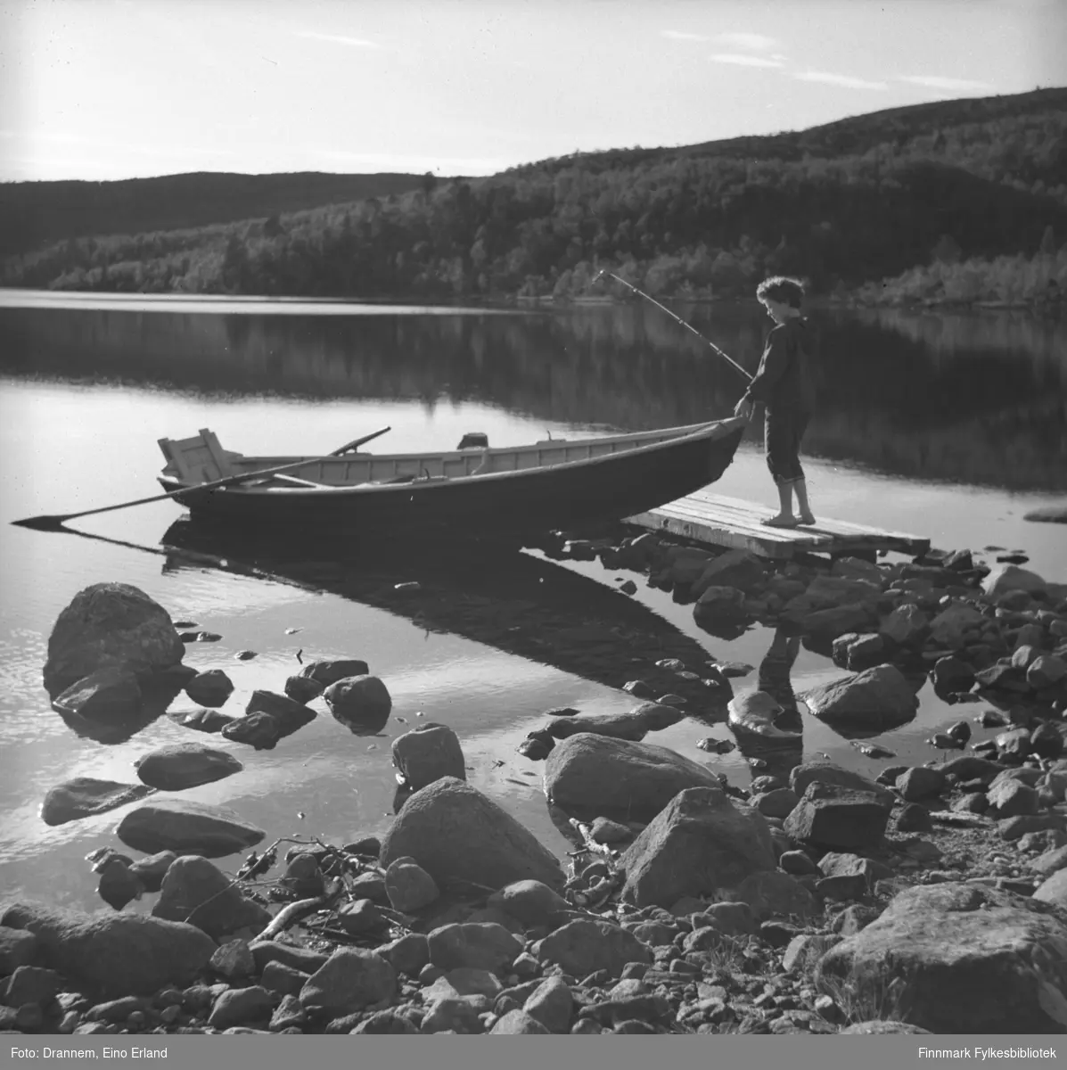 Turid Karikoski på tur ombord i en elvebåt med en fiskestang i hånda.
