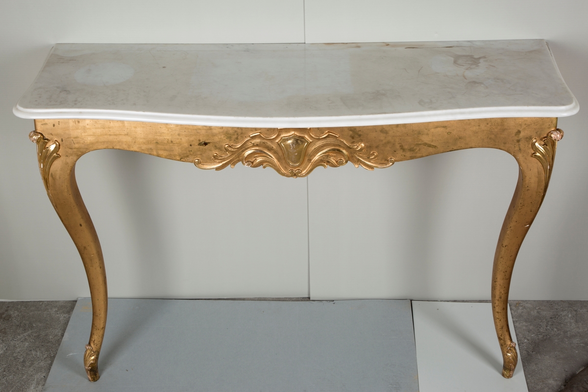 Møbelsettet består av et rektangulært sidebord og et rektangulært speil. Begge har forgylte utskjæringer. Bordet har to svugne ben og marmor bordplate.