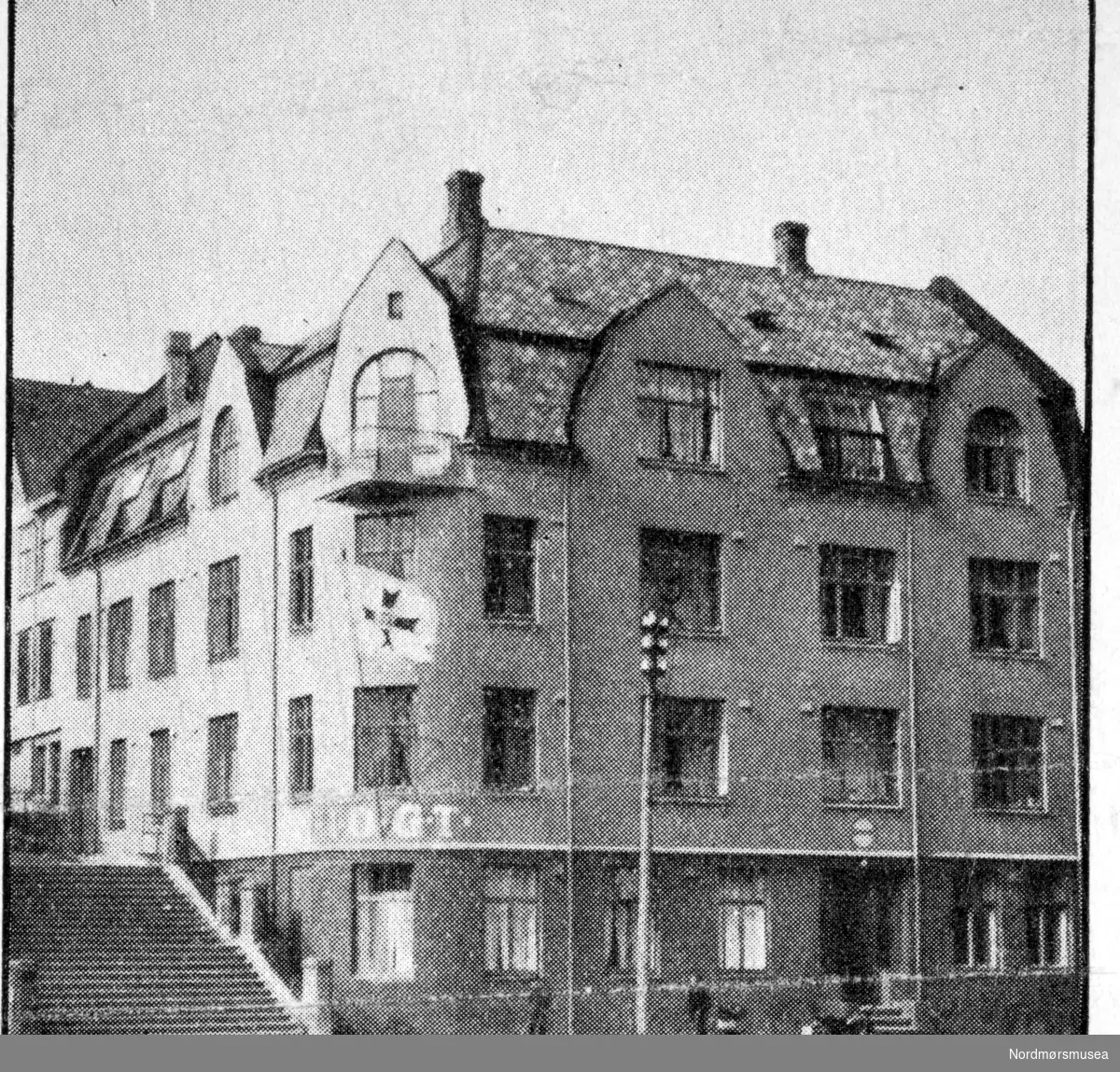 Bildet er fra krysset mellom Dr. Werrings gate og Trappegata i Kristiansund. I-O-G-T Avholdslosjen holder til i bygningen. Bildet er trolig fra 1920 årene. Ukjent fotograf. Bildet er fra Nordmøre Museums fotosamlinger. Reg: EFR
