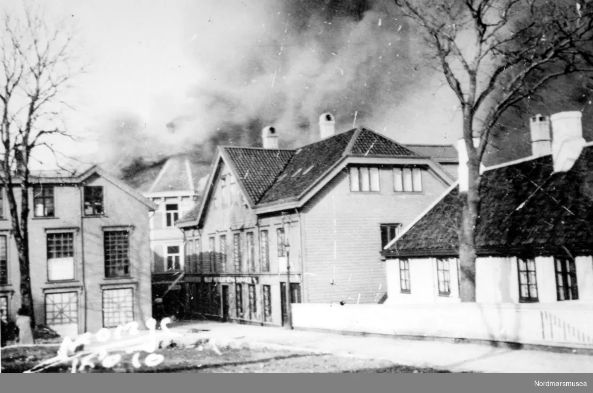 Andre verdenskrig har nettopp kommet til Kristiansund. Datoen er 28. april - 1. mai 1940, og vi ser her hus i Storgata som brenner, mens flammene nærmer seg Knudtzongården til venstre. Fra Nordmøre Museums fotosamlinger.