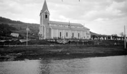 En kirke ved strandkanten. I bakgrunnen ser vi noen gårdsbru