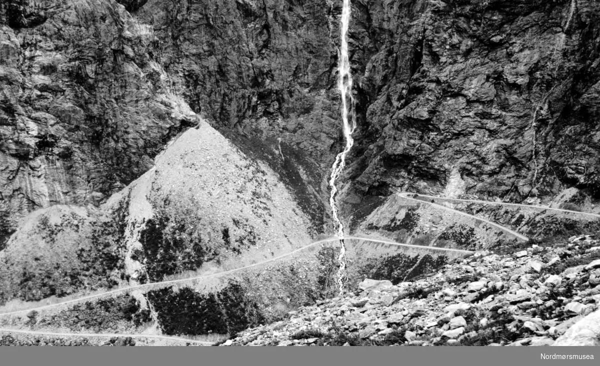 Foto trolig fra Trollstigen, med et fossefall sentralt i bildet, i Rauma kommune. Fotograf er sannsynligvis Georg Sverdrup, men datering er mer usikker; trolig fra perioden 1930 til 1939. Fra Nordmøre Museums fotosamlinger. Reg: EFR

