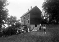 Foto av en rekke barn og voksne sittende på marken foran et 