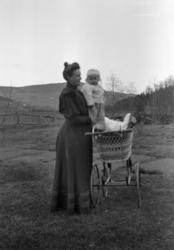 Foto av en mor, her sammen med barnet sitt ved en barnevogn 