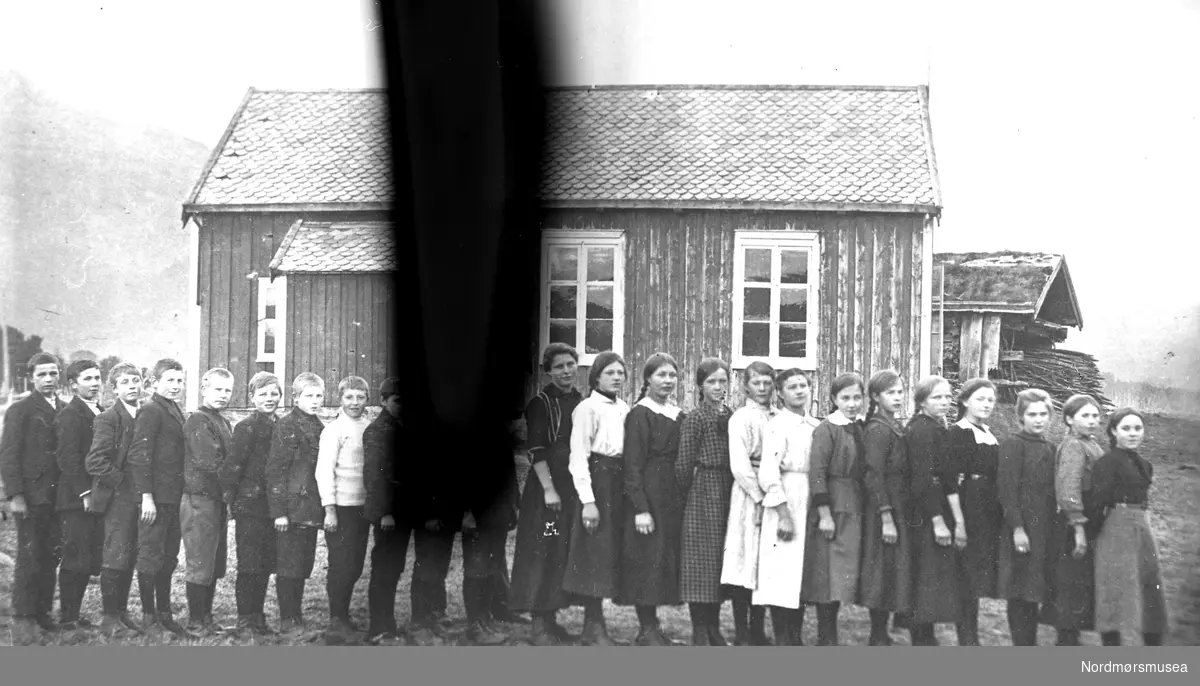 skole, første fastskole i bygda, 23 elever + lærerinne. ungdom, barn, klasse, gutter, jenter. Mulig på (Øvre) Frei. ca 1920. Fra Nordmøre Museum sin fotosamling.