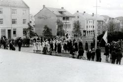 Foto fra et opptog - muligens en 17. mai? - hvor vi ser en g