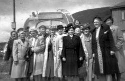 Foto av en gruppe kvinner bak en buss med registreringsnumme