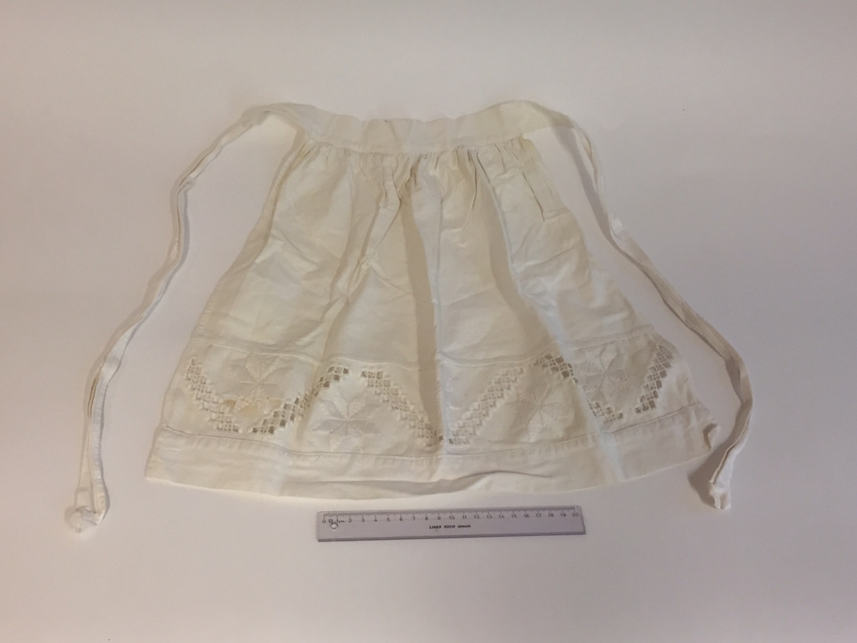 Lue, bryststykke/bringeduk og belte (C) til hardangerbunad, forkle (E) og skjorte (D) med hardangersømdetaljer.