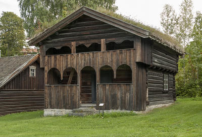 Toetasjers, relativt liten tømmerbygning med torv på taket og svalgang i to etasjer med buede åpninger.