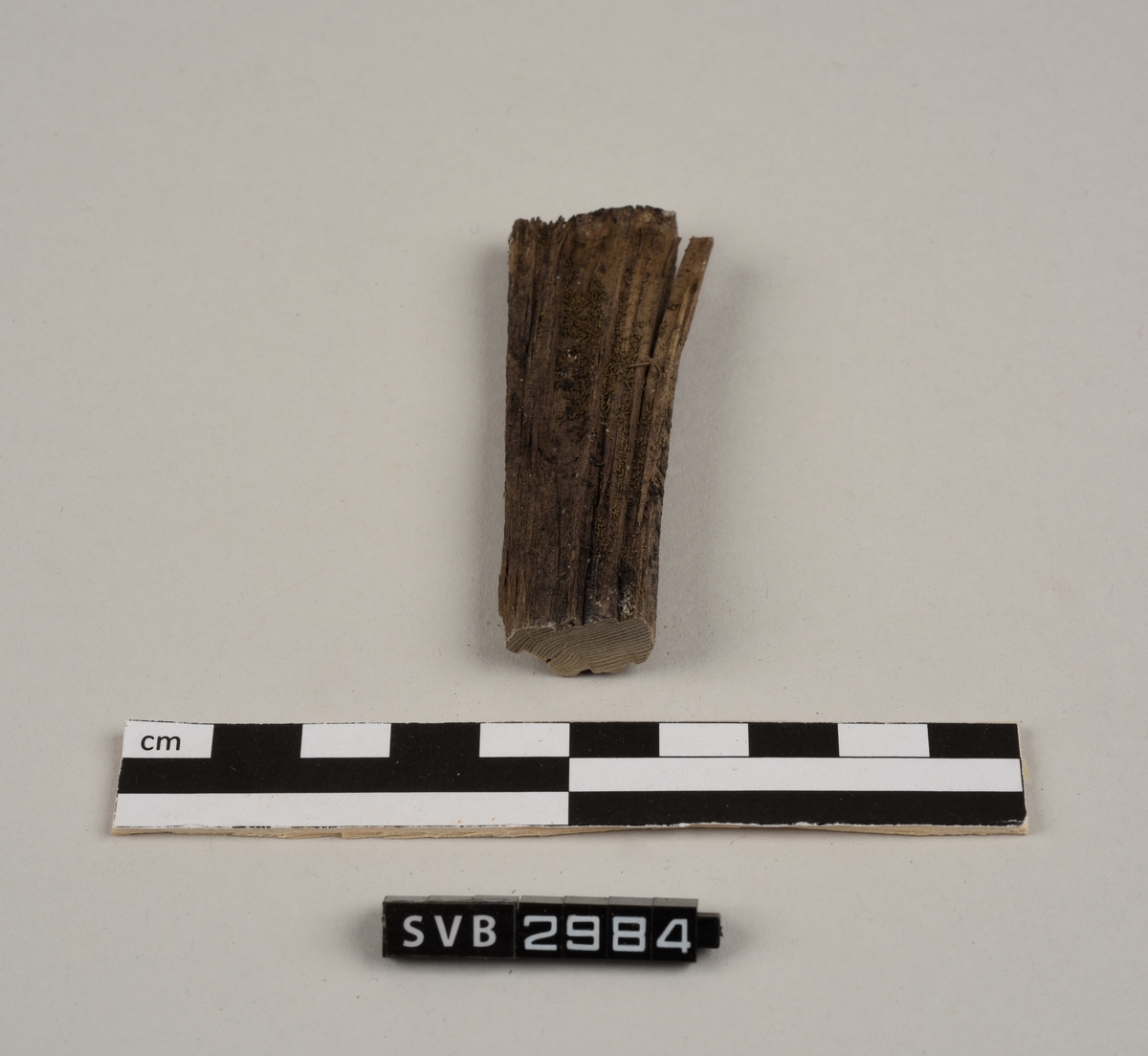 Tregjenstand med tilnærmet rundt tverrsnitt. Tremateriale er tørt og sprukkent. Det er 2 løse deler. Det er en lapp på undersiden med russiske tall og bokstaver.
