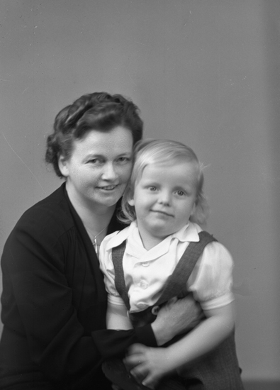 Foto av en okänd mor med en liten pojke.
Bröstbild, halvprofil. Ateljéfoto.