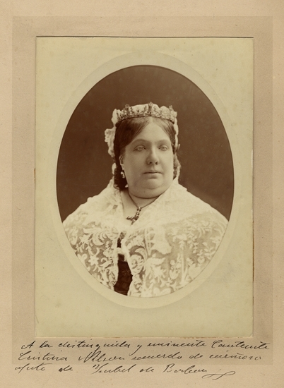 Porträttfoto av drottning Isabella II av Spanien (1832-1904) iförd juveldiadem och spetsschal.
Bröstbild, oval, halvprofil.
Med dedikation till operasångerskan Christina Nilsson på spanska.
Inskrivet i huvudbok 1953.