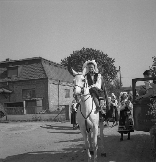 Barnens Dag, 31/5 1946.
En kvinna i Värendsdräkt rider damsadel på en vit häst,
någonstans i Växjö.