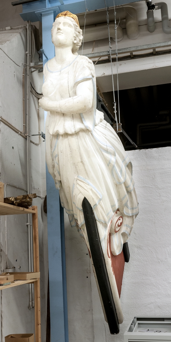 Galjonsbild, av trä. Skulptur föreställande en kvinnofigur /helfigur/ med ena handen horisontellt hållen under bröstet; den andra håller hop klädningen vid höger sida. Dräkten är av empirekaraktär /tunika/ med två knappar på vardera överarm. Håret har stor knut i nacken. Hela kvinnofiguren är vit, med blå kanter på dräkten. Framtill på huvudet ett diadem, målat i guld och rött. Den bevarade delen av fartygsbogen är svart- och rödmålad. Kvinnofiguren vilar på båda sidorna undertill på en smal slinga, vit med röda orneringar. 
Acc. kat: Galijonsbild, kvinnofigur, trä (pitch-pine), från fartyget "Cuthona" från Raumo, Finland. Förlist å Bredbädan SV om Simpnäsklubbs fyr den 15/11 1897 kl. 00.45. Var på resa från Sundsvall till Melbourne med trä.  Sedan 1897 uppställd i en trädgård, Upplandsbodarna.