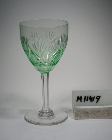 Vitvins- eller cocktailglas.
Ej identifierat.
Se M 11404 - M 11425, samma servis.
Skärslipad dekor. Facettben.
Grön kuppa, ben och fot ofärgade. Klarglas.
Ovan angivna mått avser övre diameter.
Fotdiameter: 56 mm.
Inskrivet i huvudkatalogen 1942.
Funktion: Vitvins- eller cocktailglas