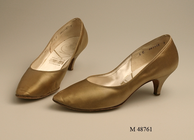 Damskor.
Ett par guldfärgade skor med klädd stilettklack. Delvis skinnfodrade.
Märkning i skon se "signering/märkning" ovan.
Sulan märkt 50.

Infört i huvudbok 1994.