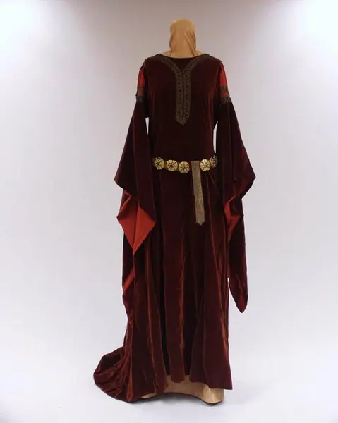 Costume for Kirsten Flagstad in the role of Isolde in Tristand and Isolde. A red dress in mediavel style with long sleeves and a gold belt around the waist.