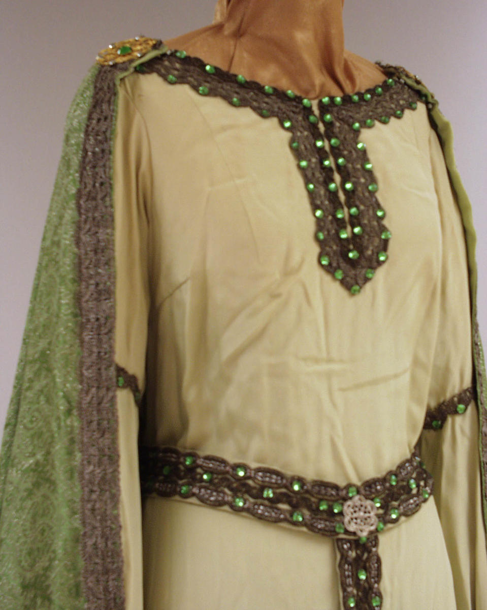 Kostyme Kirsten Flagstad i rollen som Elisabeth i Tannhauser. Hvit kjole med sorte kanter og kappe i middelalderstil. Belte rundt livet.