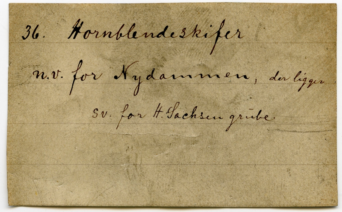 Etikett i eske:
36.
Hornblendeskifer
n.v. for Nydammen, der ligger s.v. for H. Sachsen grube.