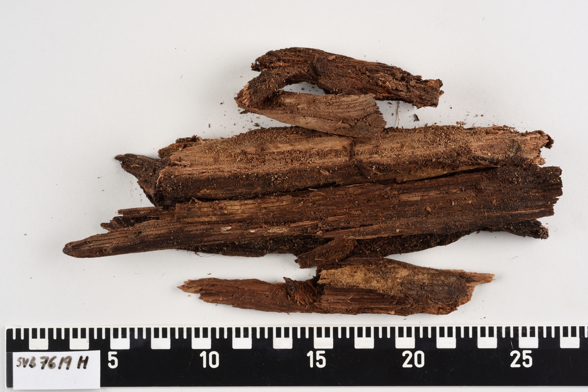 Deler av en rektangulær gravkiste. Det er kistebunnen, kistelokk, kistesidevegger og deler av hodeendegavlen.
Kistelokket er laget av et flatt og rektangulært bord som er laget av ett stykke tre. Bordet er sterkt fragmentert.
Kistesidene er i litt bedre tilstand. Bordene er avlange, rektangulære og laget av et stykke tre hver. Bordene ble festet med spiker til kistebunnen. Det er en spiker igjen i venstre sideveggen. Begge sidebordene har langsgående sprekker og er delvis brudd i flere deler.
Kistebunnen er laget av et flatt og rektangulært bord som er laget av ett stykke tre. Det er flere langsgående sprekker og flere kvisthull. Fargen er mørk brun med enkelte lysere brune partier i hodeenden.  I begge kortender er det rester etter hodegavlen og fotendegavlen og langs venstre siden er det rester etter kisteveggen. Hodeenden er bredere enn fotenden.
Hodeendegavlen er laget av en tykkere rektangulær trekube. Den har brudd opp i flere deler både på grunnen av nedbrytingen og under utgravningen.