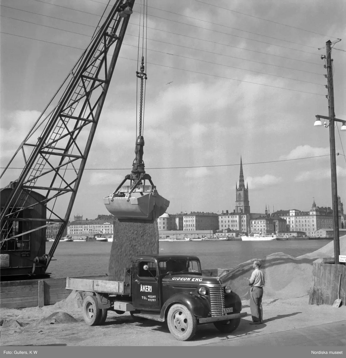 En lastbil med lastas med sand på kajen vid Söder Mälarstrand, Stockholm.