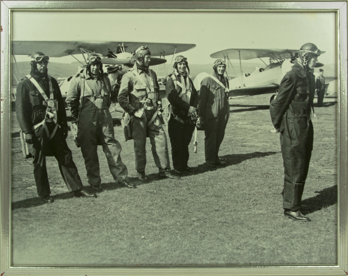 Grupporträtt. Deltagare i kurs för äldre flygofficerare på Ljungbyhed står framför skolflygplan SK 10 på ett flygfält, 1936. Inramat foto.