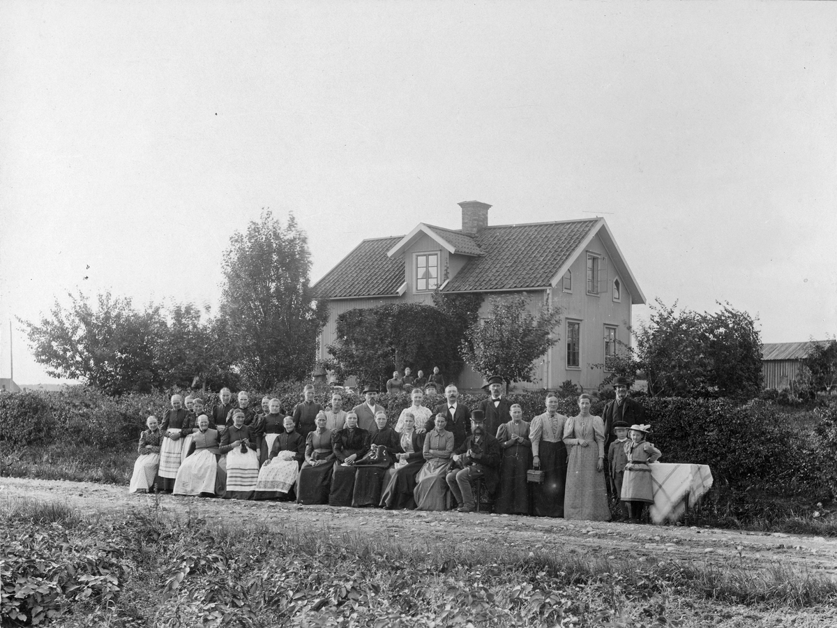 Gruppfoto utanför hus, kring sekelskifte 1800-1900