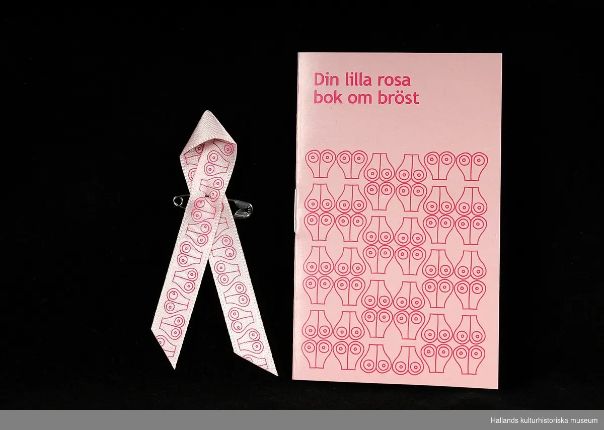 Fem stycken rockmärken i form av "Rosa Bandet". Smalt rosa textilband", vikt och sammansatt i mitten med en liten säkerhetsnål av metall. Bandet och en liten textbok ligger i en plastficka. Utvalda formgivare ger bandet olika utseende varje år. a) 2010, Liselotte Watkins (bröst). b) 2012, House of Dagmar (hjärta). c) 2013, Elsa och Helene Billgren (fingeravtryck) d) 2015, Clesson Koivisto Rune arkitektkontor (cirkel). e) 2016, Alicia Wikander (våg)