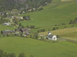 Olstad kapell, hvitmalt med kirkegård. Mo gård bak. Videre s