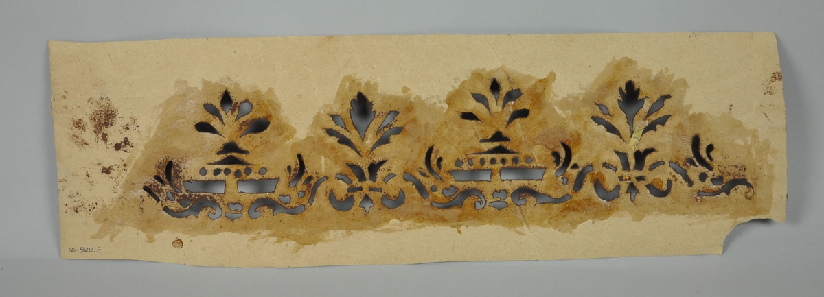 Malersjablong av papir med rester av brun maling.