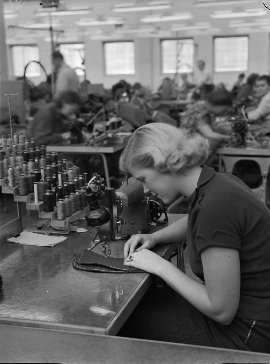 Kvinna vid arbetsbänk på läder/ textilfabrik.