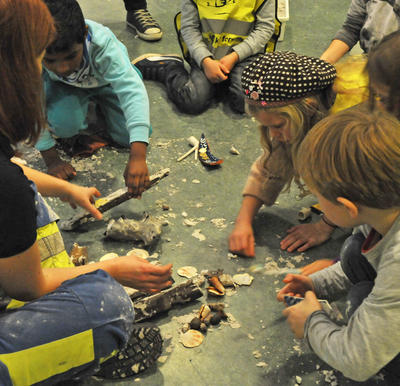 Barn sitter i sirkel, leker arkeologer, graver ut funn fra sandkasser.. Foto/Photo