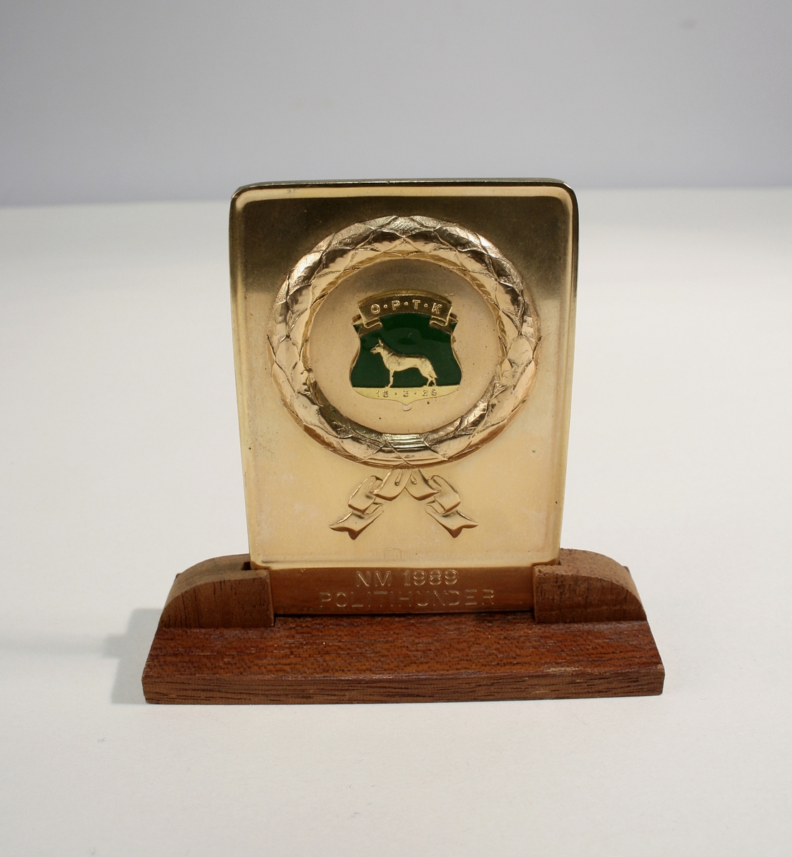 En metallplakett på tresokkel, et sølvfat, to knapper. Eske fra sølvsmed Knut Larsen, merket "Politihunden Giell"