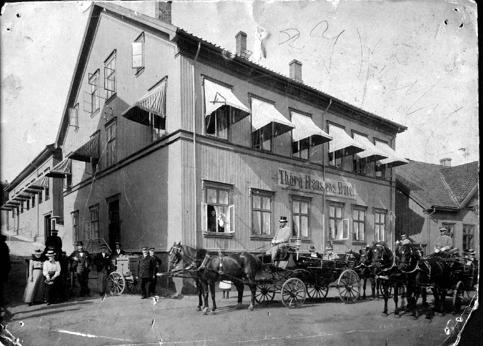 Storgata med hestekjøretøy, hester, drosje, kusker, foran Thora Hansens hotell.