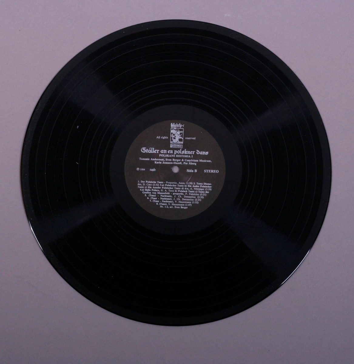 Grammofonplate i svart vinyl og plateomslag i papp. Plata ligger i en papirlomme. Teksthefte i papir.