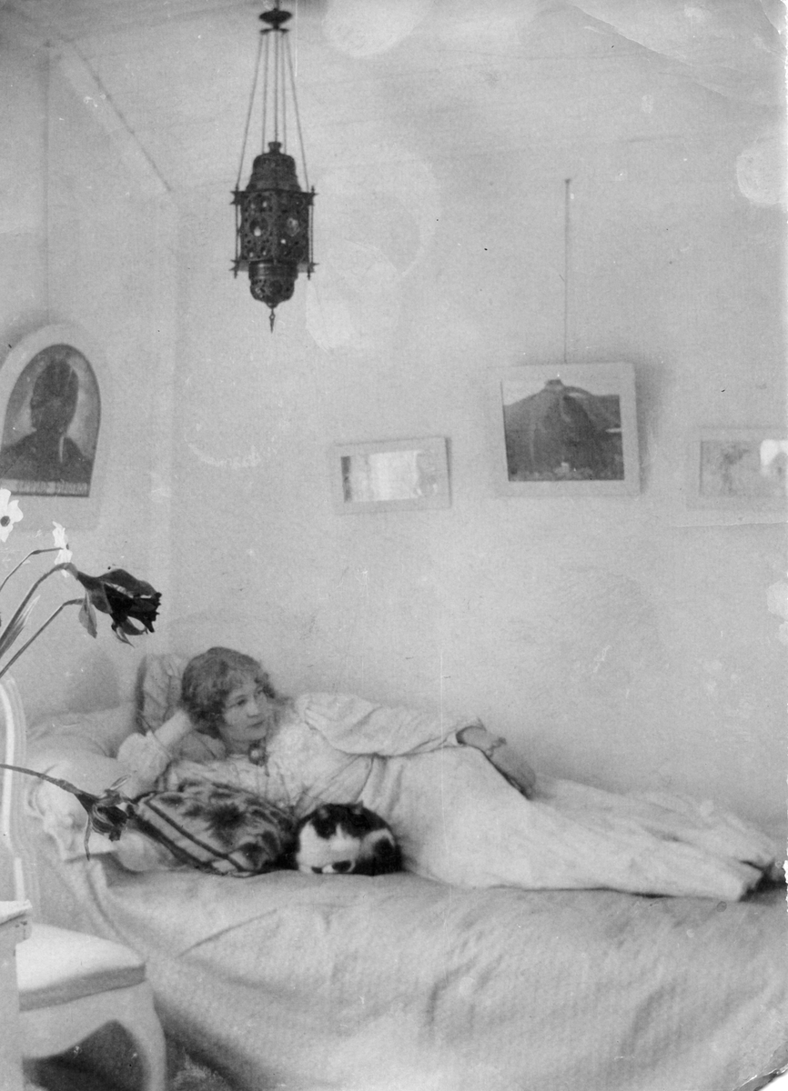 Ester Bauer (född Ellqvist) ligger på en säng tillsammans med en katt i blå rummet i stugan de hyrde i Torstorp utanför Gränna.