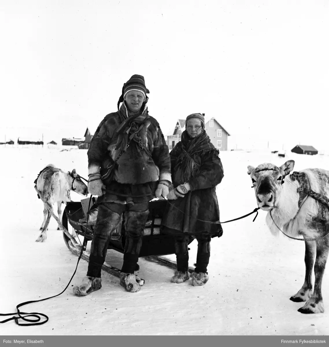 Mikkel Mikkelsen Logje og Inger Anne Magnusdatter Sara  fotografert foran sleden med kjørerein på hver side, i Kautokeino påsketider 1940.