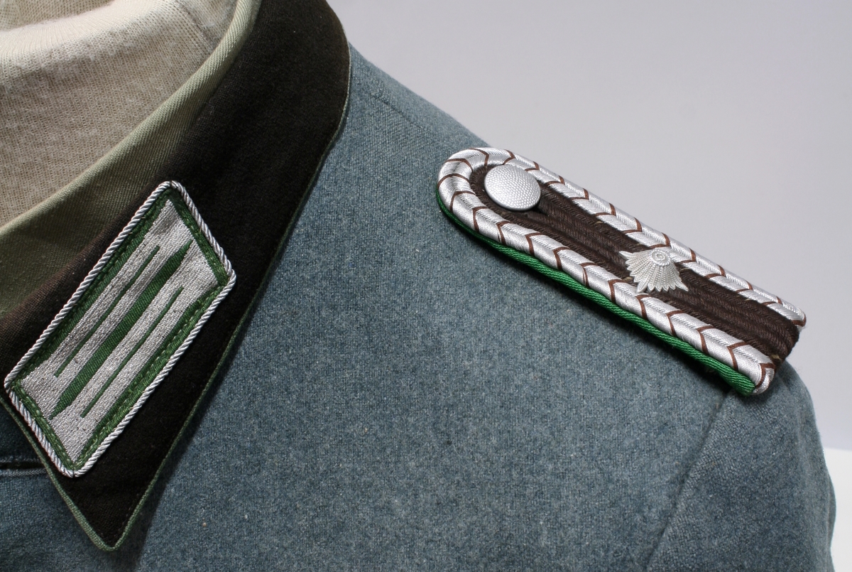 Full uniform med støvler. På brystet har den en pins (Politiets dag 1942), en bånd (Minne-/deltakermedalje 1914-1918) og EK. 2. klasse bånd. Den har også fløyte i brystlommen. 

Skulderdistinksjoner til en oberwachtmeister

I lommen var det stoff lapper og sytråd med nål. 

På beltet har den pistolhylster med Walther PP magasin.