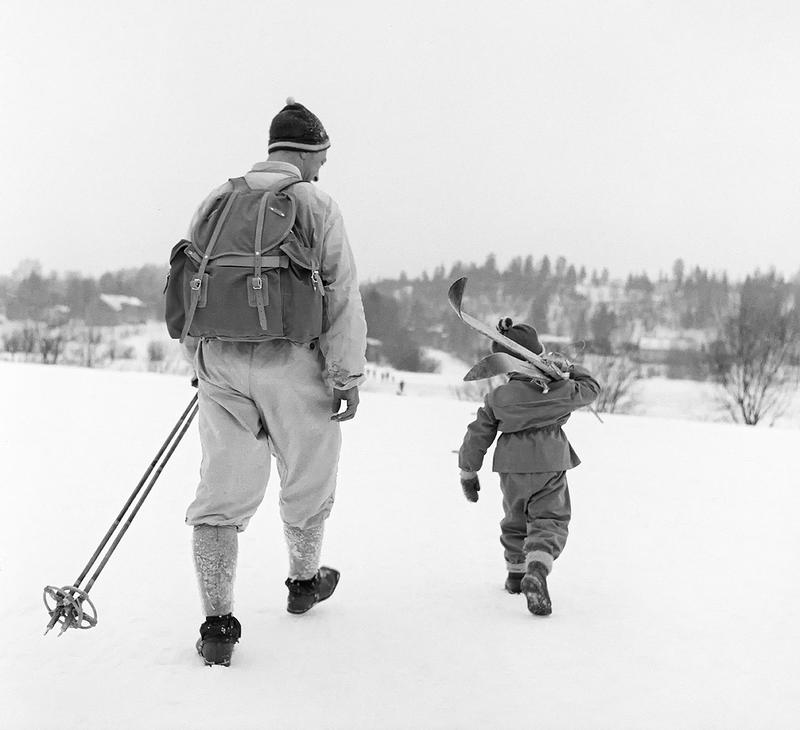Bilde tatt på Birkebeinerrennet i 1959. Liten gutt bærer farens ski på skuldrene