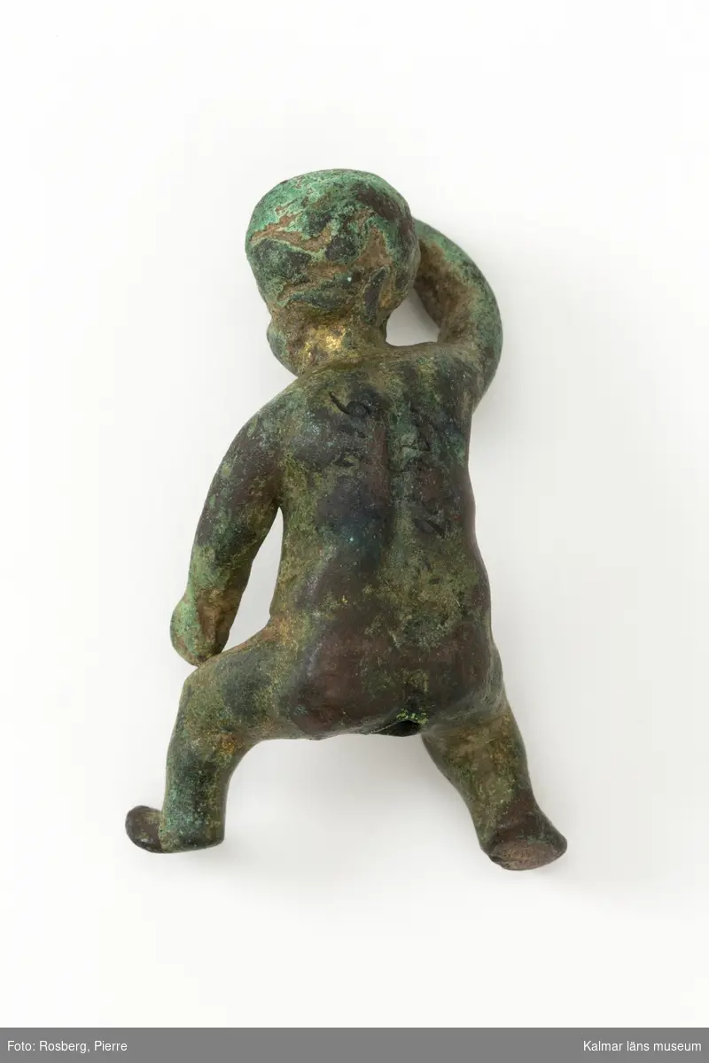 KLM 12716 Figurin, putto, av brons, med spår av förgyllning. Gjuten. Ett sittande barn, flicka. Romerskt arbete?