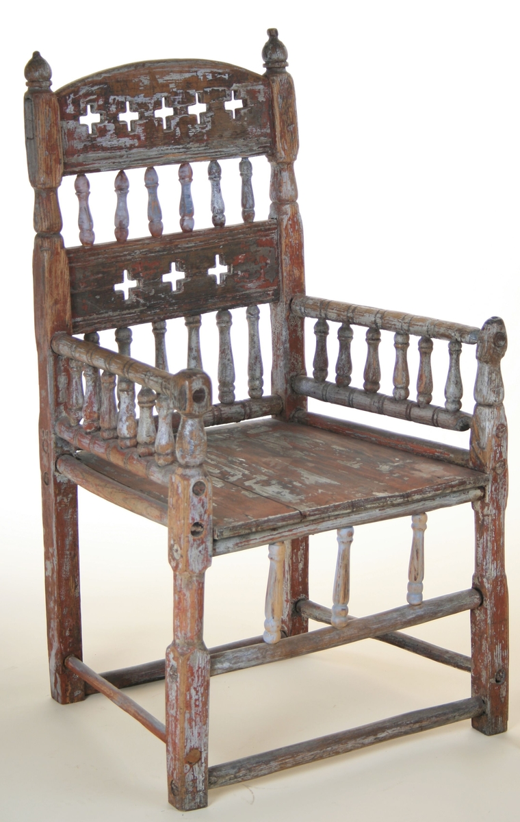 Senmiddelaldersk type, av dreiede pinner. Muligens opprinnelig kirkestol, da der er rader med kors i ryggen. Armlenene har på undersiden festet 6 små  balustre, som nedentil er festet i nok en dreiet tverrligger. Der har likeledes vært balustre (3 stk) under sargen i fronten ned til den øvre tverrstreber. Ryggen består av avvekslende dreiede balustre i tett  rad og horisontale bretter med utskårne gjennombrutte kors. Buet toppstykke. Endene av bakstavene har dreide knotter.