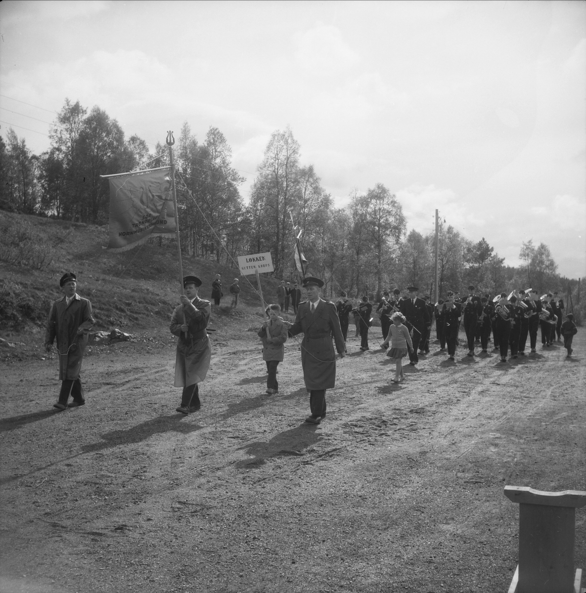 Løkken Guttemusikkorps marsjerer. Sør-Trøndelag Hormusikkforbund med fane foran.
Musikkstevne 1957 ved Festiviteten på Løkken.