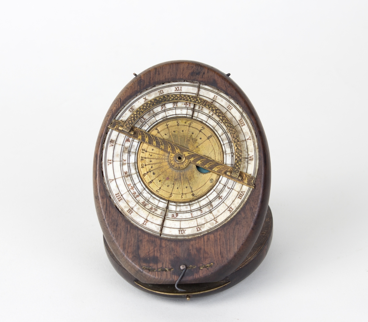 Instrument for måling av månefaser og solens hellning. Ovalt treobjekt som holdes oppe av en tynn messingpinne, sammelagt ligger to like store ovale treskiver oppå hverandre. På oversiden er det en klokkelignende rund måleskive (astrolabe?) i metall. Treskive to inneholder to kompassliknende skiver som er nedfelt i treverket.