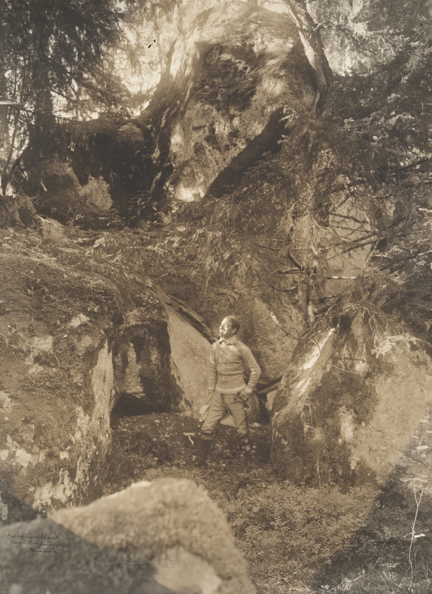 John Bauer står utanför en grottöppning i skogen utanför Bunn i Gränna.